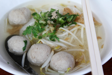 Clear water noodles with meat ball in white bowl.