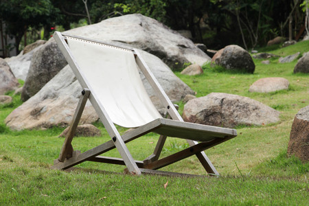 Wooden deckchair on green grass.