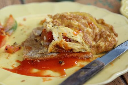 Breakfast; omelet, bread and ketchup on the side on yellow plate.の写真素材