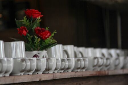 Many white ceramic coffee cups on a open  wooden shelf.の写真素材