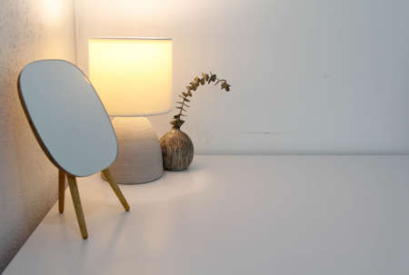 White table lamp,  mirror and flower pot on the wooden table.の写真素材