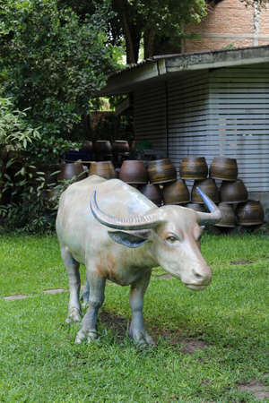 A white buffalo statue standing on green grass.