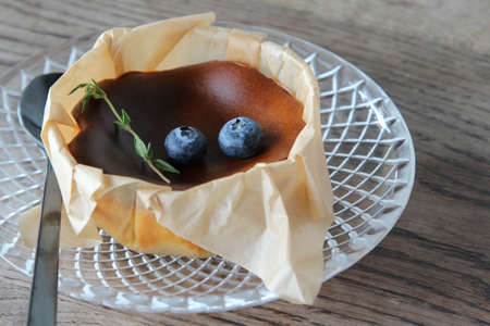 A custard cake in paper cup on glass plate.