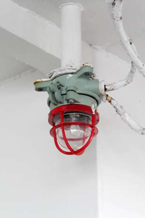 Red and grey steel lamp on marine ship.