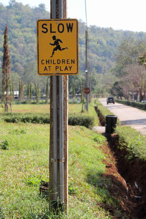 "SLOW CHILDREN AT PLAY" yellow road street sign in rural country.の写真素材