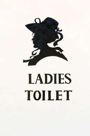 "LADIES TOILET" black sign on white concrete wall.の写真素材