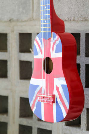 The Great Britain flag acoustic guitar hanging on the block wall.の写真素材