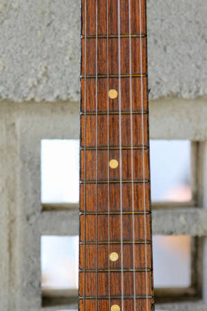 The acoustic guitar hanging on the block wall.