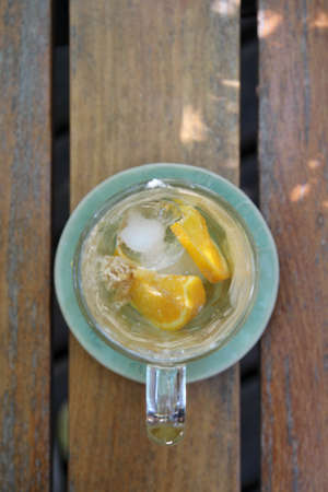 A glass of iced coffee with orange sliced after drinking on wooden table.の写真素材