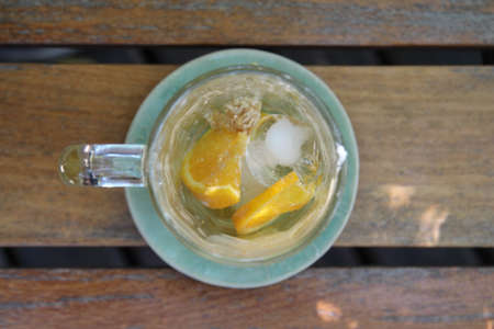 A glass of iced coffee with orange sliced after drinking on wooden table.の写真素材