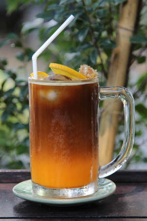 A glass of iced americano black coffee mixed with orange juice on wooden table.の写真素材