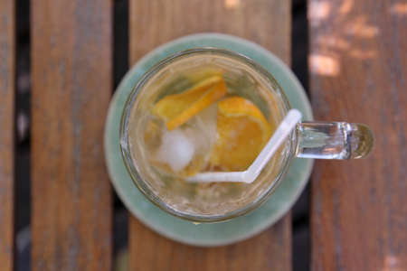 A glass of iced coffee with orange sliced after drinking on wooden table.の写真素材