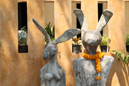 Two rabbit statues standing in front of the orange concrete wall.の写真素材