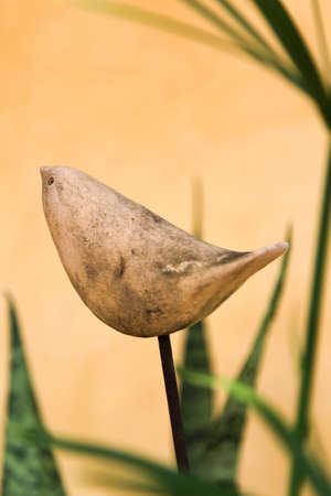 A small bird statue against orange background.の写真素材