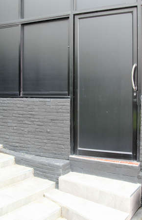 Black aluminum windows and door on gray brick wall.の写真素材