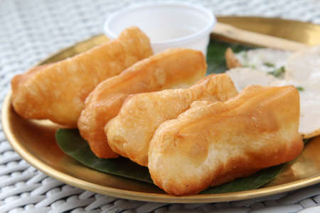 Fried patongko and Kanom krok or coconut-rice pancake on golden plate.