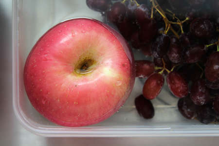 The fresh apple and grape in the water to wash before eating.の写真素材