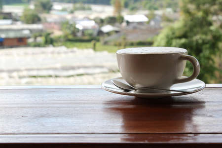 Hot cappuccino in white cup on wooden tableの写真素材