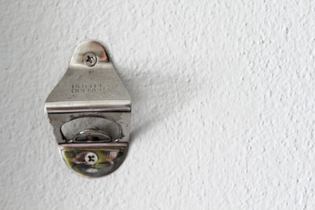 Stainless antique bottle opener install on white concrete wall