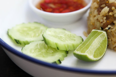 Fried rice with cucumber, lime and chilli fish sauce in white ceramic plateの写真素材