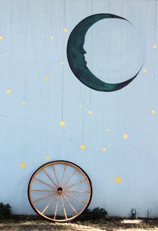 An old bicycle wheel rests against the blue concrete wallの写真素材