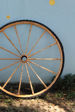 An old bicycle wheel rests against the blue concrete wall