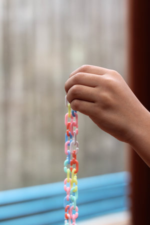 A little boy is playing with colorful plastic chain toy