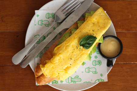 Slice avocado, toast with omelet on white plateの写真素材