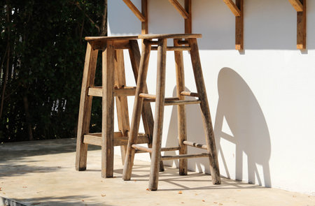 Two wooden chairs placed in front of white concrete wallの写真素材