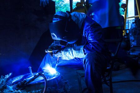 Worker with protective mask sparks piping weldingの写真素材