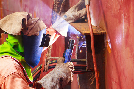 Male  worker wearing protective clothing and repair welding industrial construction oil and gas or  storage tank inside confined spaces.の写真素材