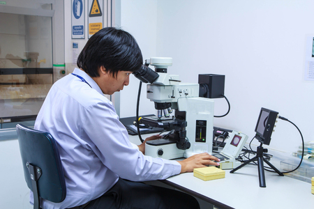 Bangkok - June 24th, 2016 : An Asian male structural engineer metallurgy researcher using he microscope in a laboratory.のeditorial素材