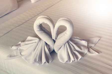 The swan towels on the bed in a hotel room.の写真素材