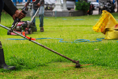 Man worker cutting grass with at the lawn.