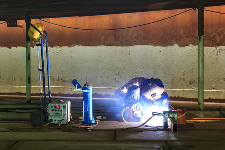 Male  worker wearing protective clothing and repair welding industrial construction oil and gas or ...