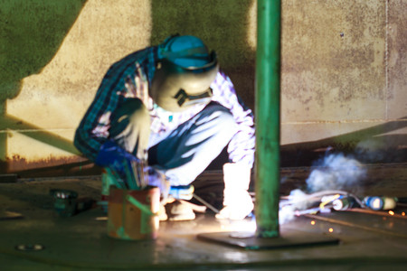 Blurred photo Male  worker wearing protective clothing and repair welding industrial construction...