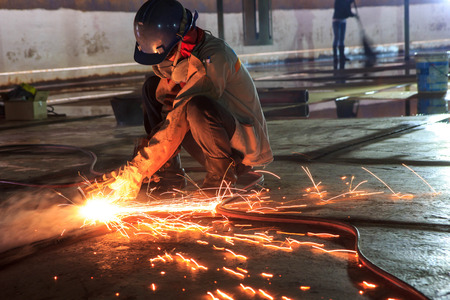 Bangkok Thailand - September 10th, 2016: Male  worker wearing protective clothing and Cutting sparks  industrial construction oil and gas or  storage tank inside confined spaces.のeditorial素材
