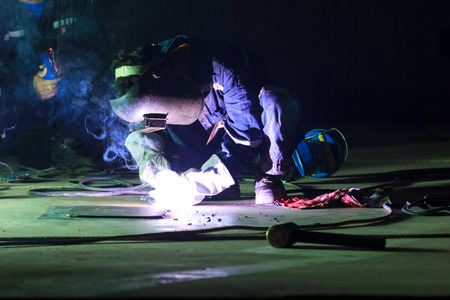Male  worker wearing protective clothing repair  bottom plate storage tank industrial construction...
