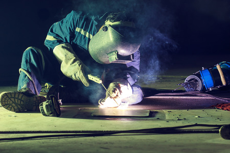 Male  worker wearing protective clothing repair  bottom plate storage tank industrial construction...