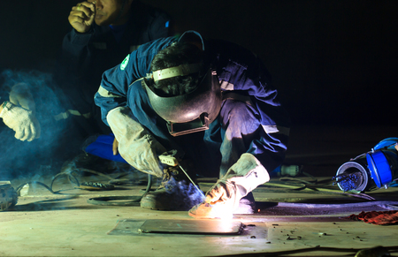 Male  worker wearing protective clothing repair  bottom plate storage tank industrial construction...