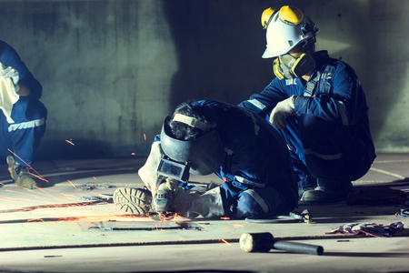 Male  worker wearing protective clothing repair grinding bottom plate storage tank industrial construction inside confined spaces.の写真素材