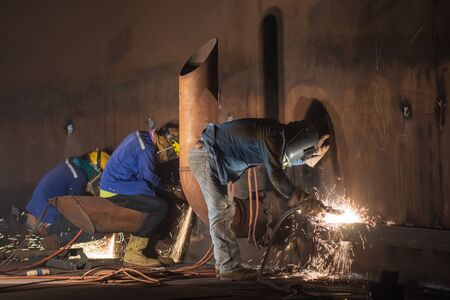 Male three worker wearing protective clothing and repair  welding tank shell plate storage tank...