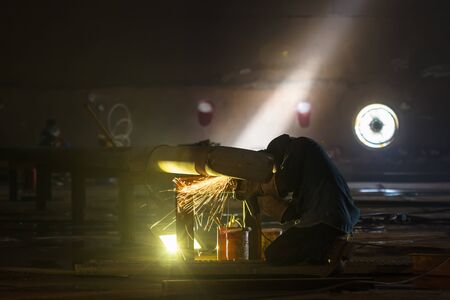 Male worker wearing protective clothing and repair  welding pipeline storage tank inside confined...