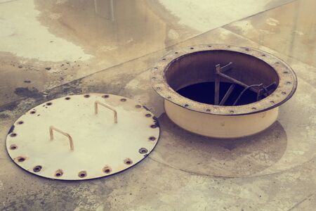 Opened rusty manhole on the white fuel tank roof deck storage tank confined spaceの写真素材