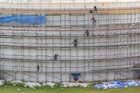 Construction workers installing scaffolding storage tank.の写真素材