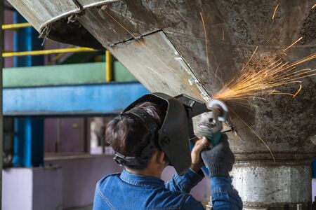 Worker grinding repair stainless silo bottom tank