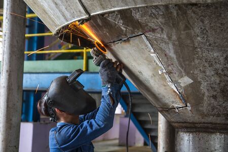 Worker grinding repair stainless silo bottom tank