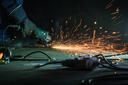 Male worker wearing protective clothing and repair grinding  storage tank bottom plate inside...