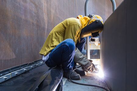 Male  worker wearing protective clothing and repair welding industrial construction oil and gas or ...