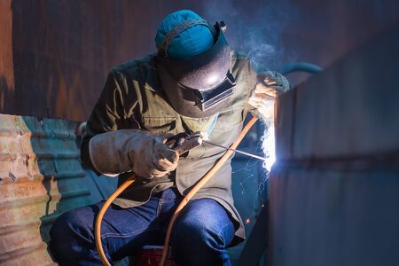 Male  worker wearing protective clothing and repair plate tank  oil welding industrial construction...